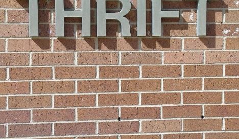 Sign displaying the word "thrift" on a brick wall